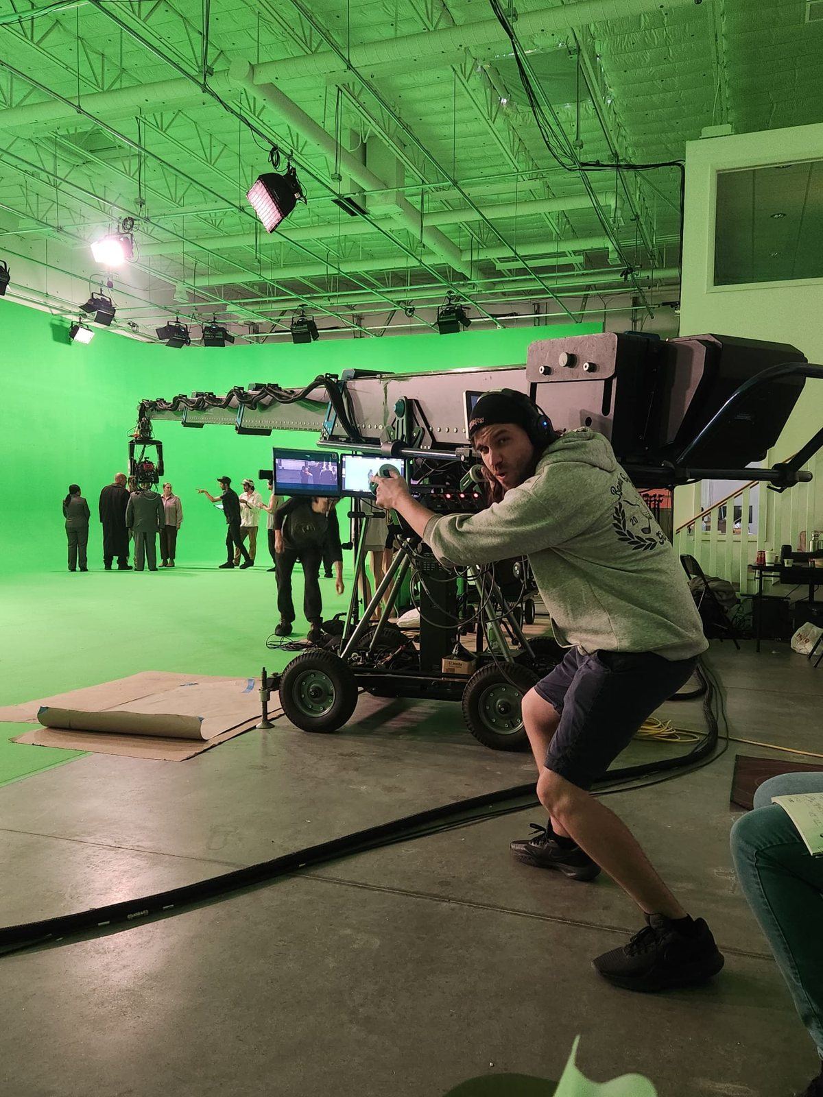 Camera and lighting crew working a dolly-mounted crane setup on the ABQ Castle Studios stage while the company rehearses