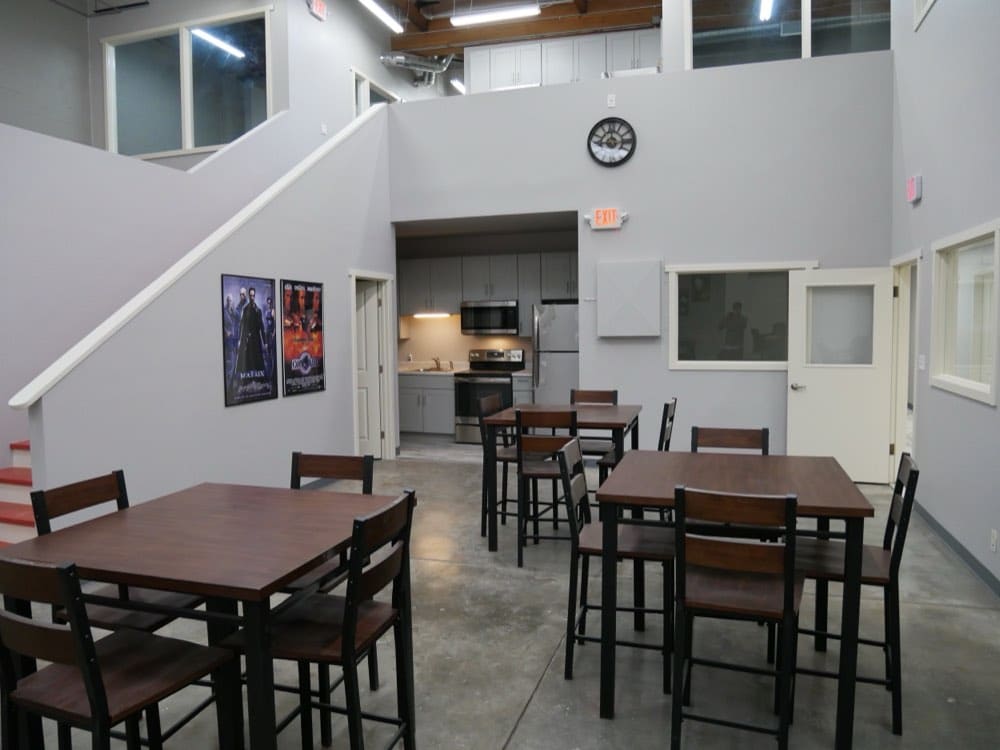 The crew kitchen and dining area at the Burbank studio, with high-top tables beneath the mezzanine