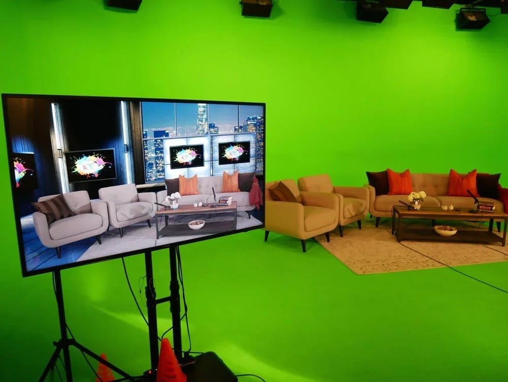 Real sofas and a coffee table on the Burbank green screen, blended into a virtual talk-show set on the monitor
