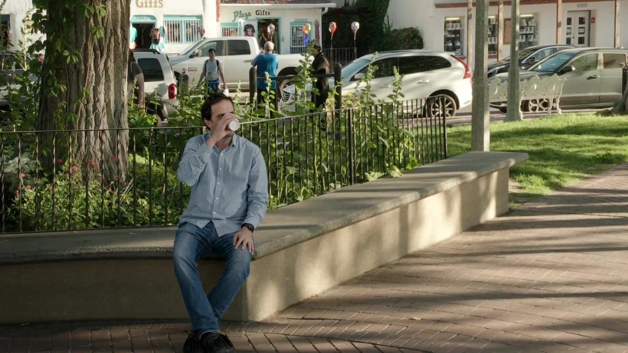 An actor sitting on the plaza wall with a coffee, composited live, in camera, into the Old Town Albuquerque capture