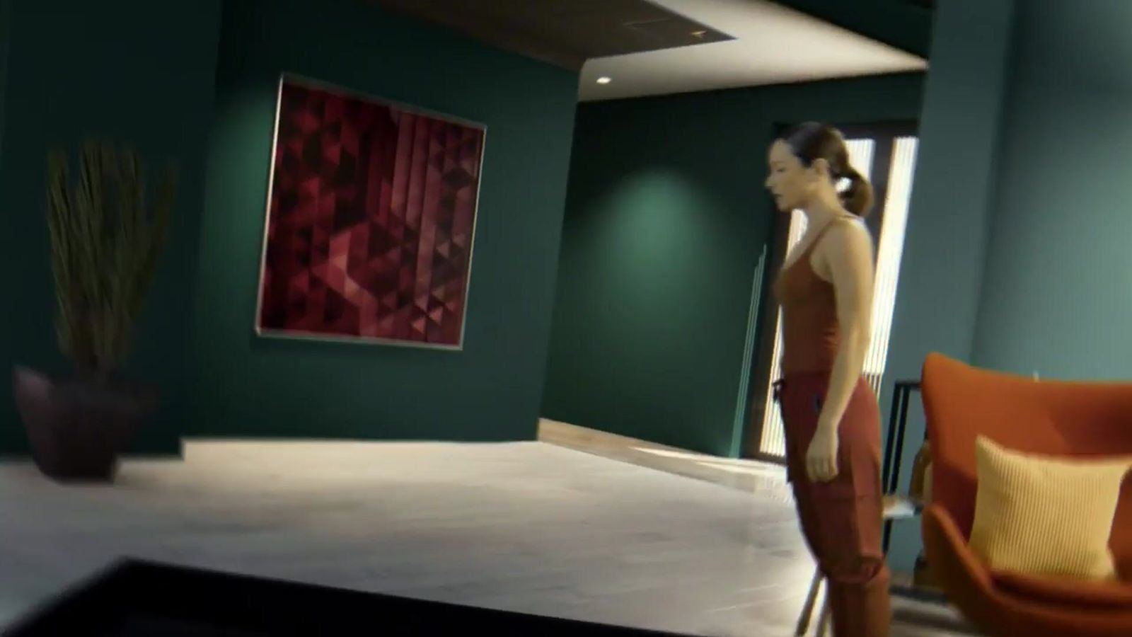 Commercial: a woman in a modern living room with dark green walls and an orange armchair, a virtual set at L.A. & ABQ Castle Studios