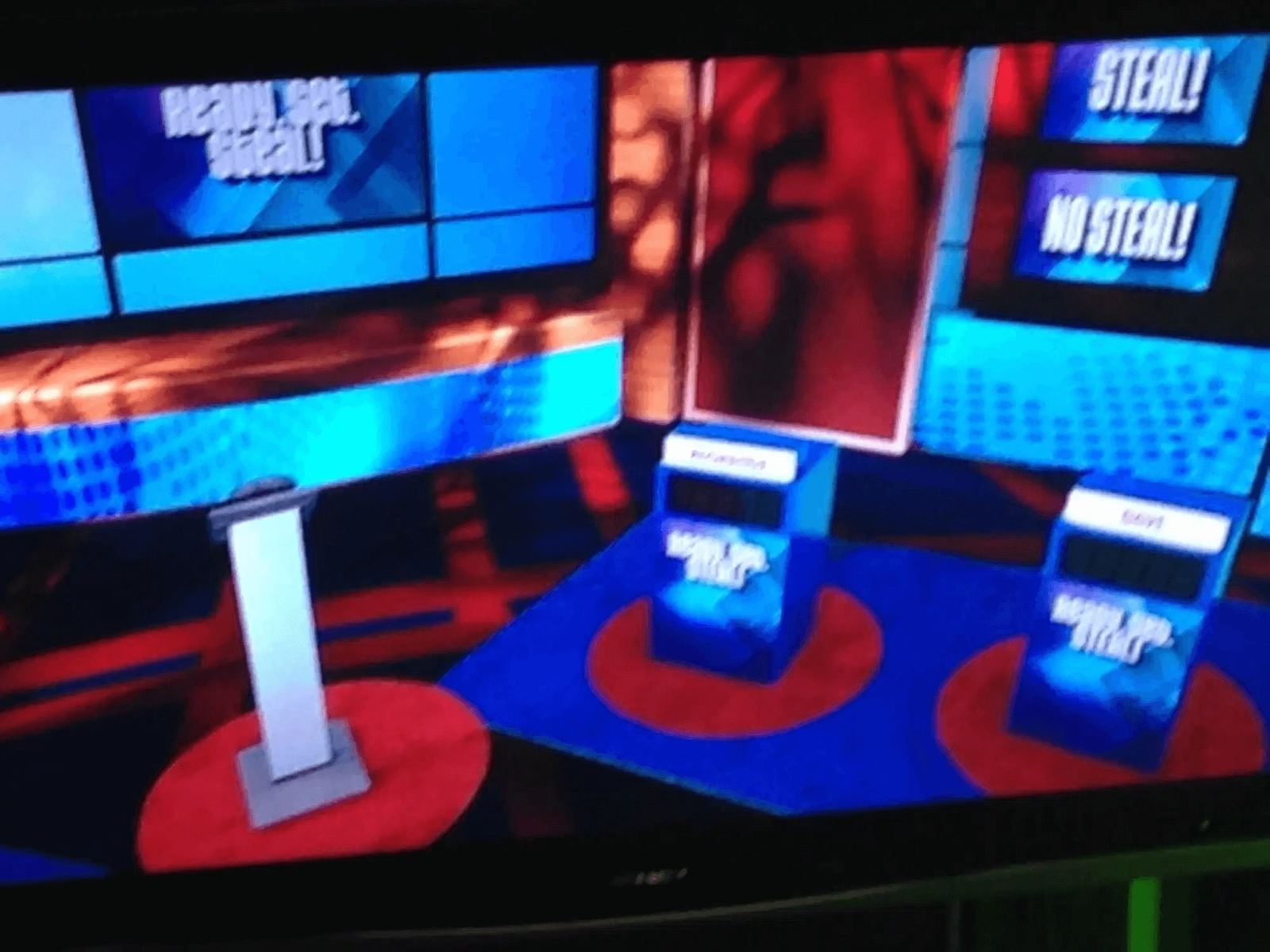 Game show set — a 'Ready, Set, Steal!' contestant podium stage in red and blue shown on a monitor at L.A. & ABQ Castle Studios