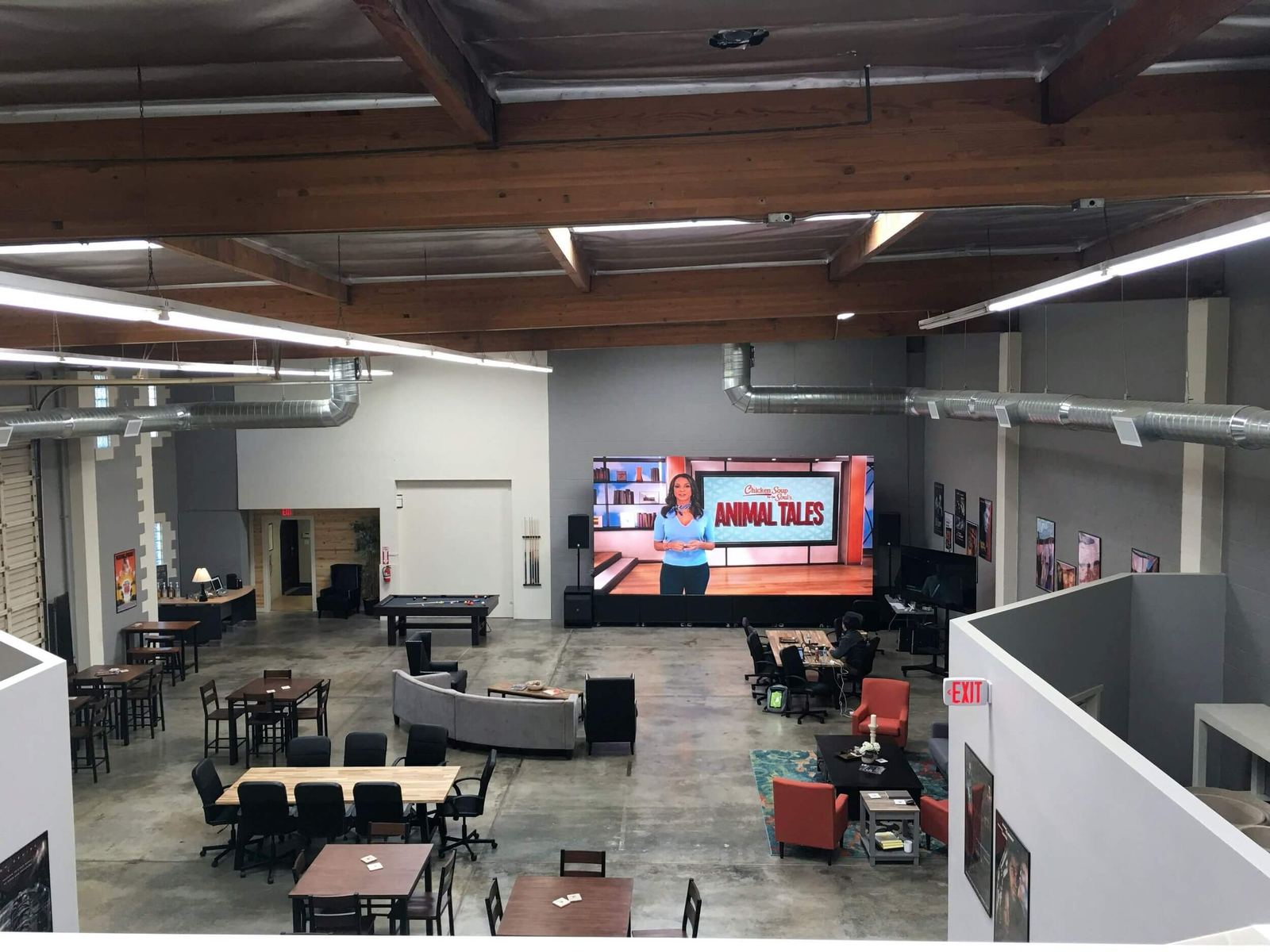 Host wrap: the Burbank studio's common area seen from the mezzanine, with an 'Animal Tales' host segment playing on the giant LED video village wall