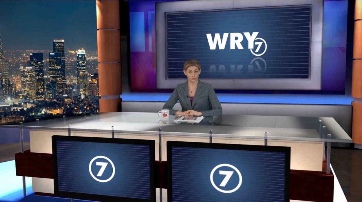 News set — a news anchor at a glass-topped 'WRY 7' desk before a skyline window and station-branded video wall, a virtual production set at L.A. & ABQ Castle Studios