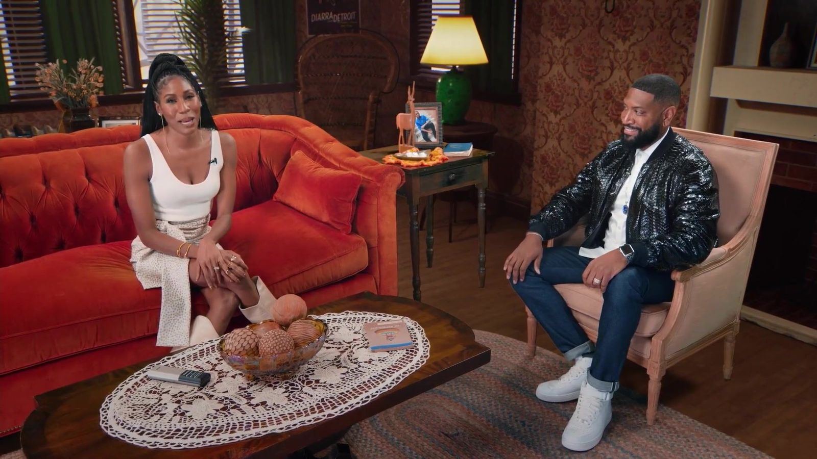 Press junket: a wider angle of the living room interview set with an orange sofa and fireplace, press junket coverage at L.A. & ABQ Castle Studios