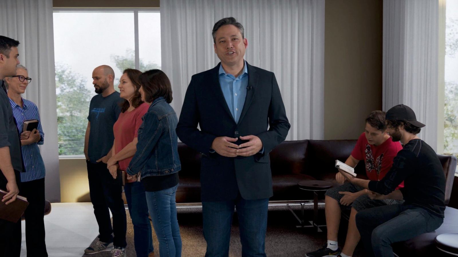 TV and film set — a host addresses a small group standing in a bright modern living room, a virtual production set at L.A. & ABQ Castle Studios