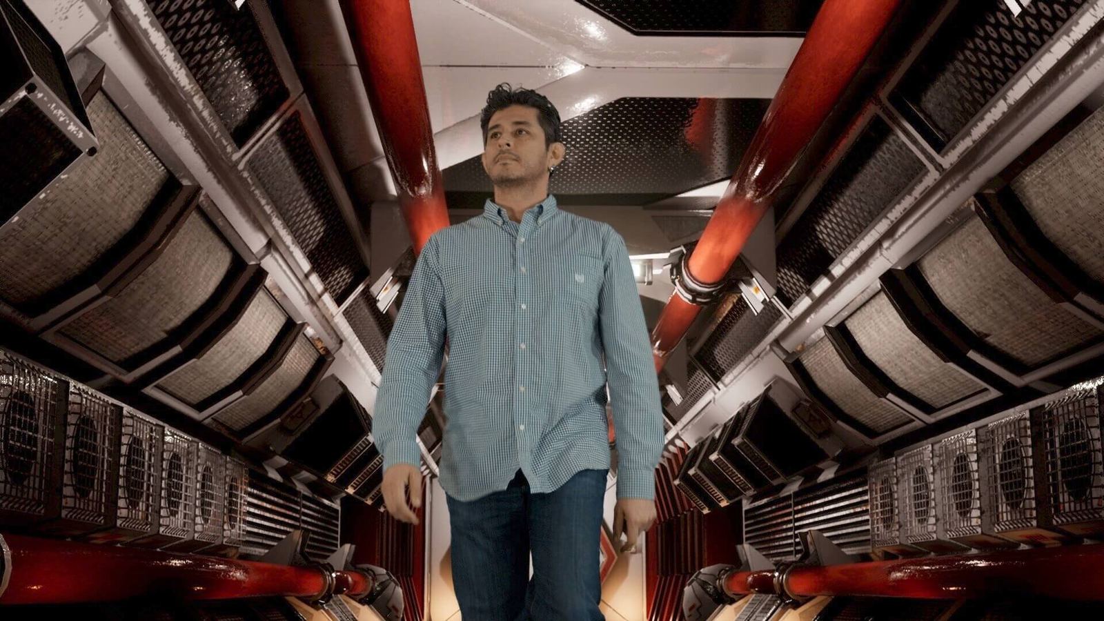 TV and film set — a man walks down a glowing mechanical corridor lined with red pipes and vents, an Unreal Engine virtual production set at L.A. & ABQ Castle Studios