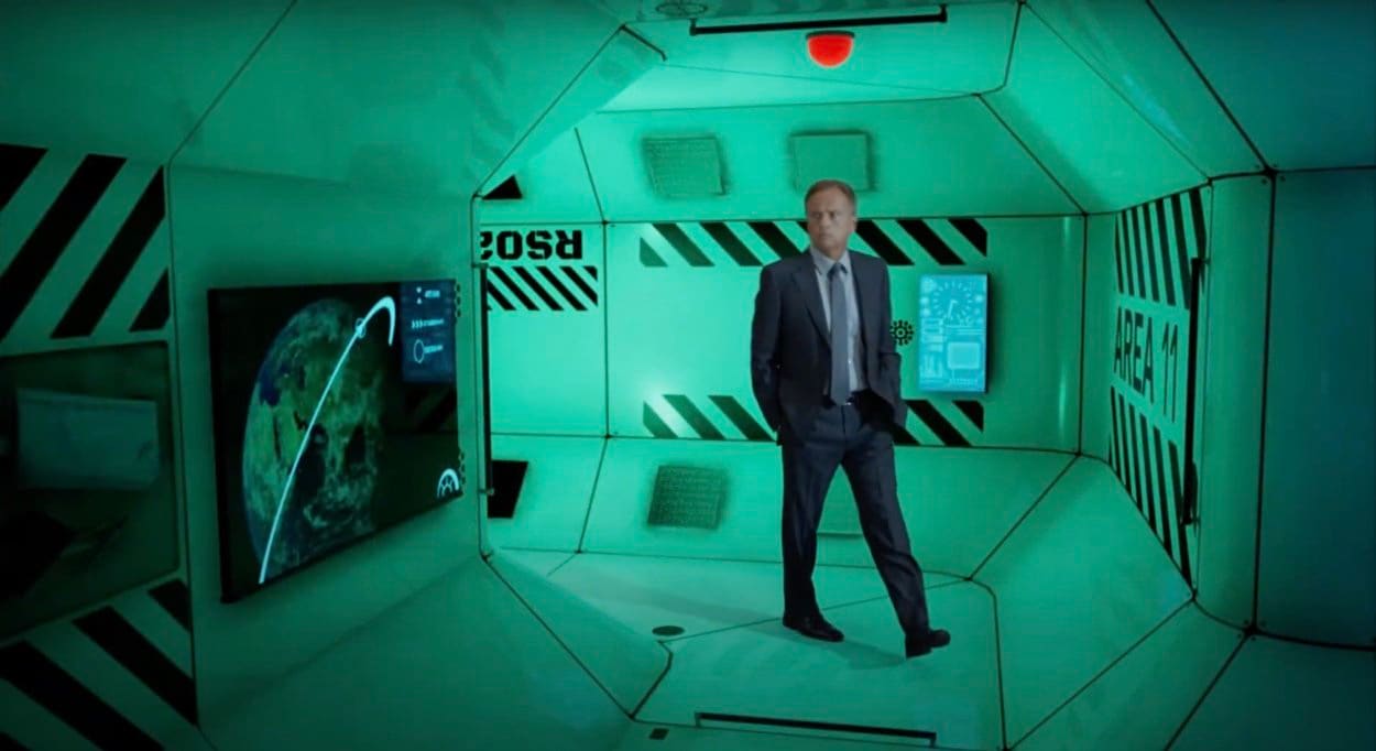 Unreal Engine set — an actor in a suit in a green-lit space station module with an Earth-orbit display, a virtual production set at L.A. & ABQ Castle Studios