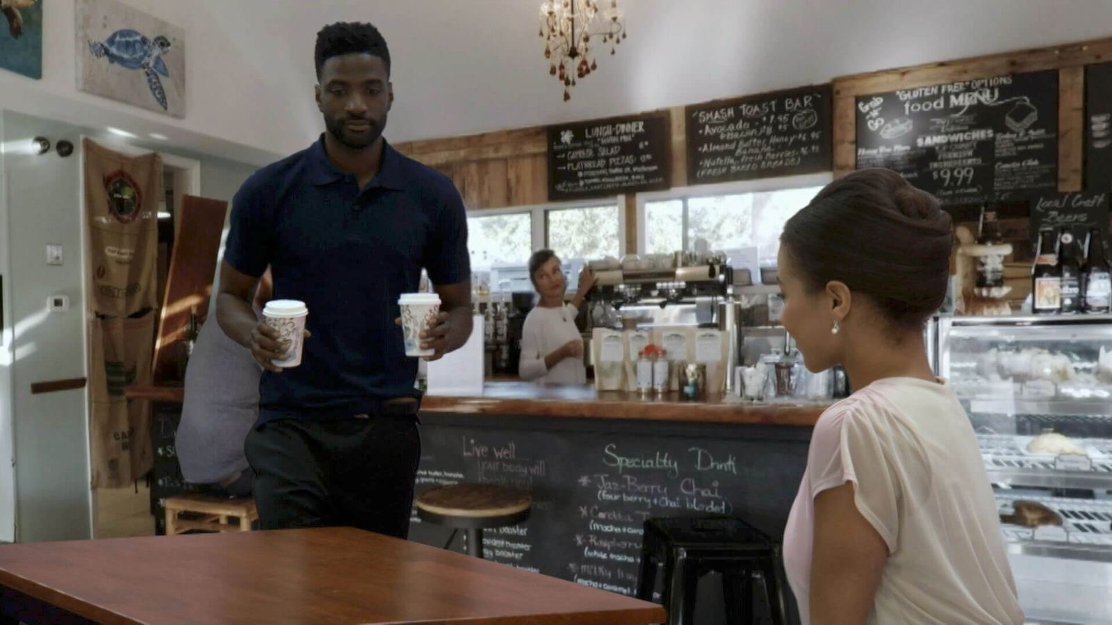 Two actors share coffee in a rustic coffeehouse, a photoreal virtual standing set at L.A. & ABQ Castle Studios